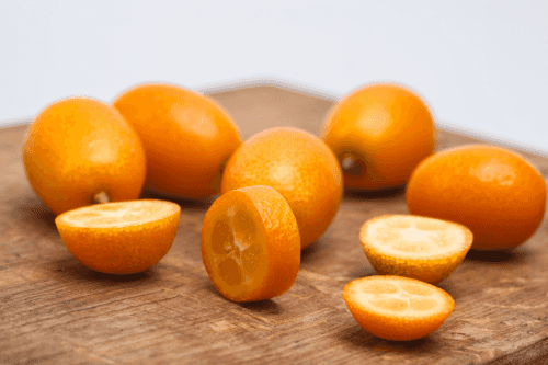 Kumquats gelegen in een houten lepel. Een kumquat is doormidden gesneden zodat je het vruchtvlees kan zien