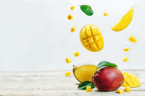 Gesneden stukjes mango vallend op een hele mango Mango is ‘de’ vrucht om je calorie inname te beheersen