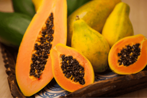 Grote en kleine papaya's in een houten kratje.