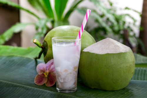Groene kokosnoten liggen op een tafel met een glas kokoswater ernaast.