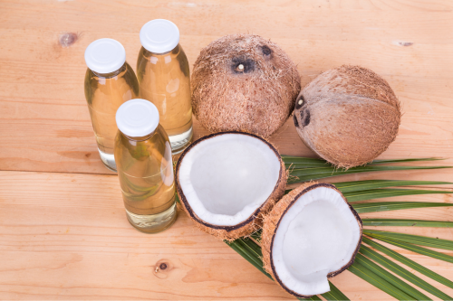 extra virgin en biologische kokosolie in flesjes met kokosnoot vruchten ernaast 7. Feitjes over het gebruiken van bio kokosolie